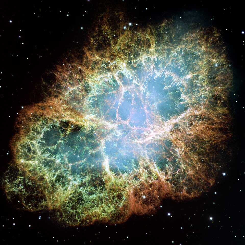 The Crab Nebula in visible light — a roughly oval cloud of orange and green filamentary gas surrounding a diffuse blue interior, set against a starfield