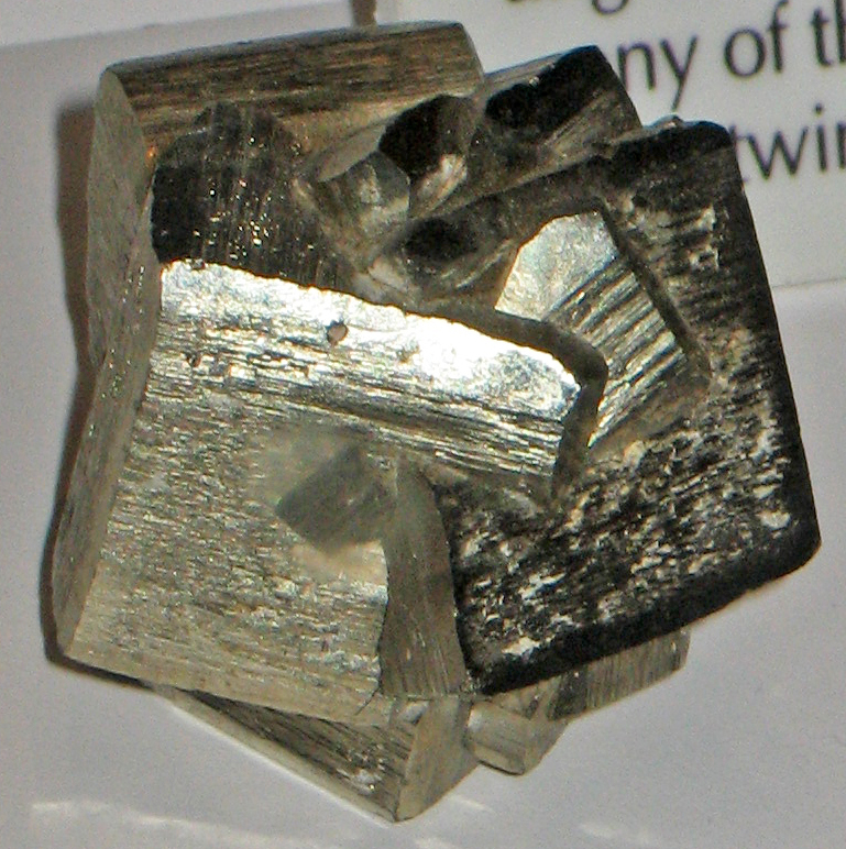 A specimen of pyrite made of intergrown brass-yellow metallic cubes, their flat faces finely striated and catching the light