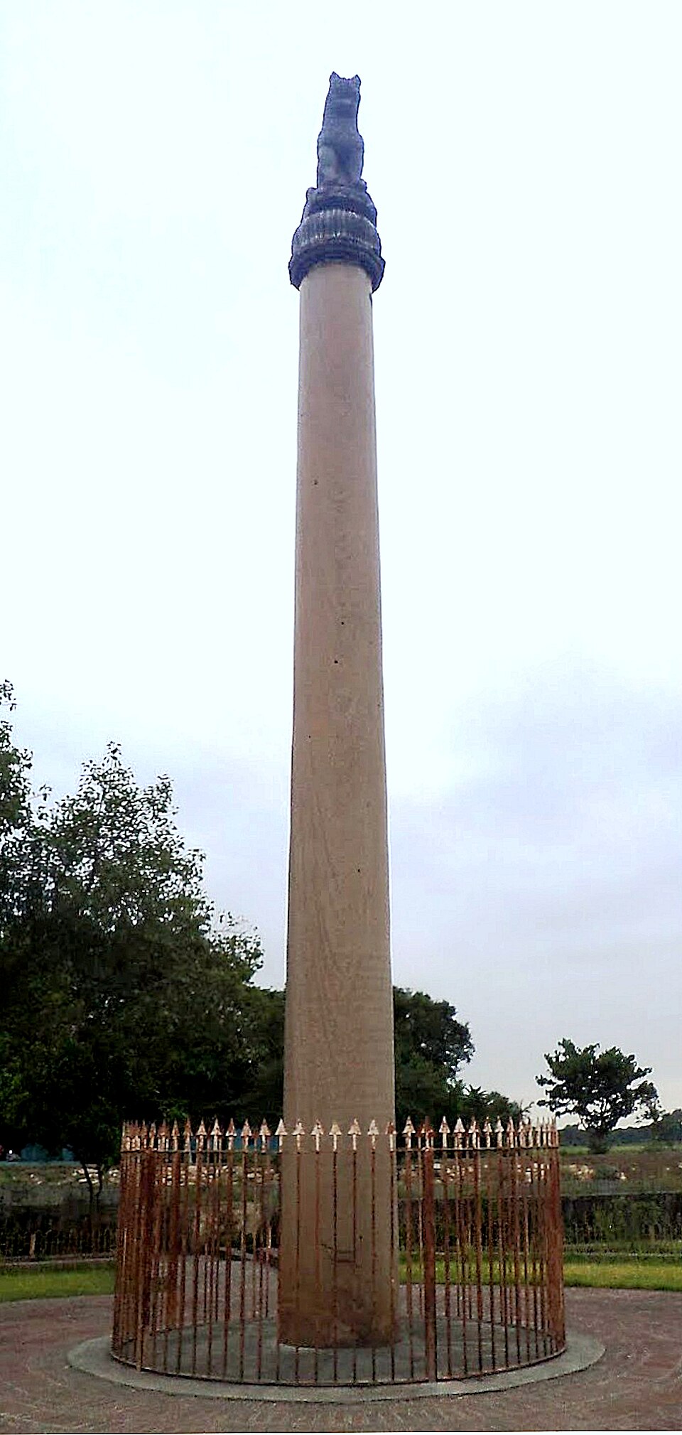 The tall polished monolithic Ashokan pillar at Lauria Nandangarh standing inside a circular iron railing, topped by its seated lion capital