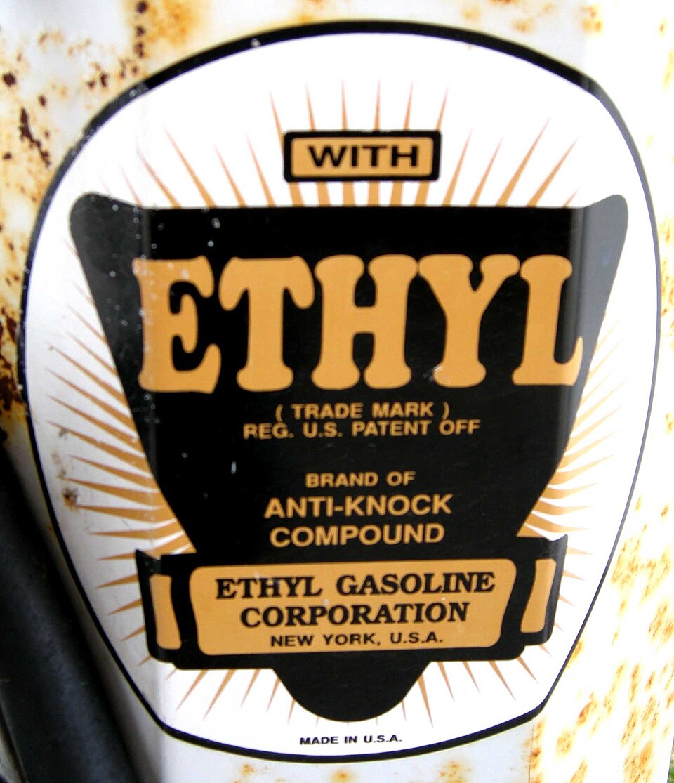 The enamel 'Ethyl' badge on a rusting vintage petrol pump, its sunburst emblem reading WITH ETHYL, BRAND OF ANTI-KNOCK COMPOUND, ETHYL GASOLINE CORPORATION, NEW YORK, U.S.A.