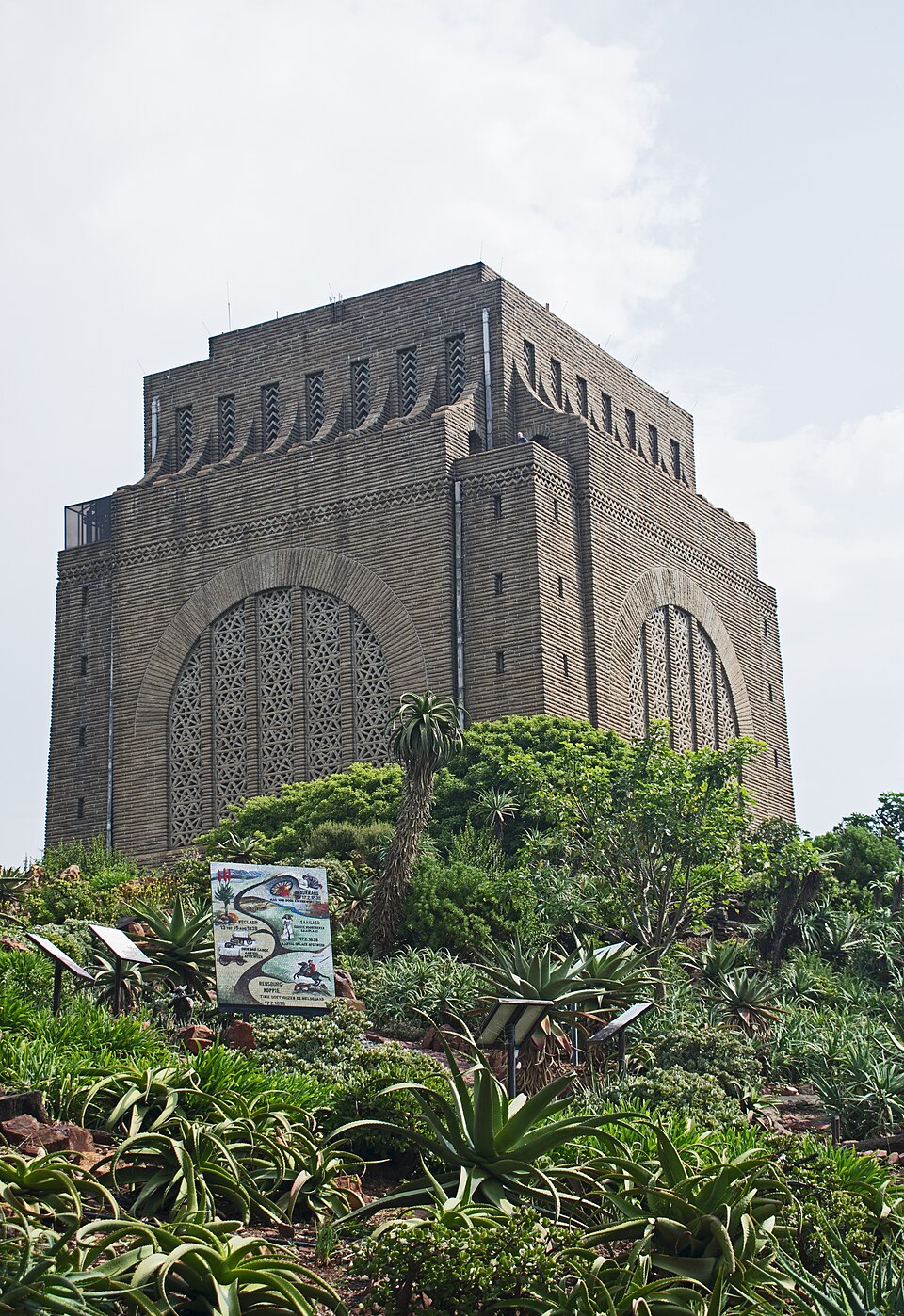 The Voortrekker Monument in Pretoria, a massive square granite block with large arched openings and a stepped cornice, rising above an aloe garden on Monument Hill