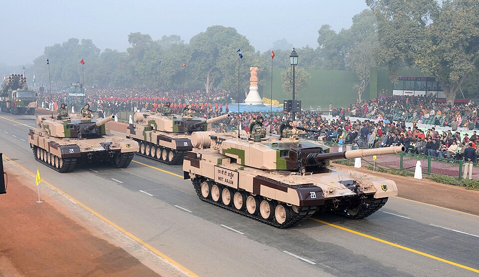 Three Indian Army Arjun main battle tanks in desert and green camouflage rolling down Rajpath in the Republic Day parade, the nearest lettered MBT ARJUN on its hull side