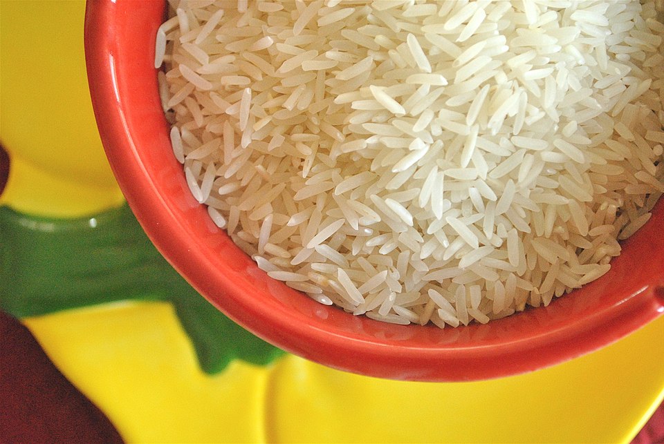 A bowl of uncooked long-grain white basmati rice, the slender translucent grains filling the dish