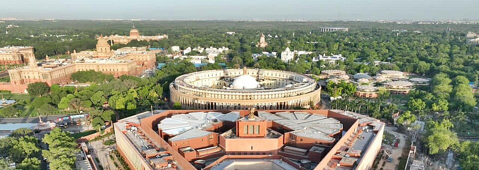 Aerial view over the Parliament complex in New Delhi with the new triangular Sansad Bhavan in the foreground and the older circular colonnaded building, now Samvidhan Sadan, immediately behind it