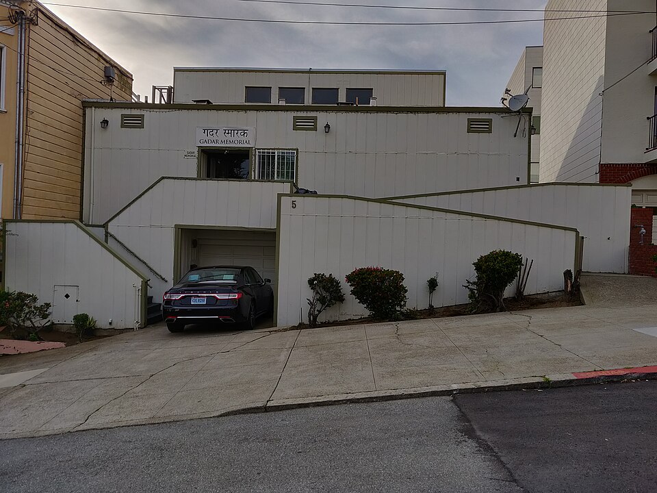 The Ghadar Memorial building at 5 Wood Street, San Francisco, a plain white-boarded house with a stairway to the first floor and a sign reading 'गदर स्मारक / GADAR MEMORIAL' above the door