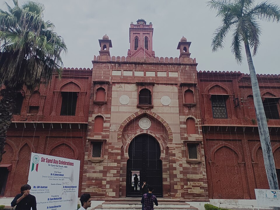 The Victoria Gate of Aligarh Muslim University: a red-sandstone gateway with a pointed arch lettered VICTORIA GATE, flanked by chhatris and topped by the campus clock tower