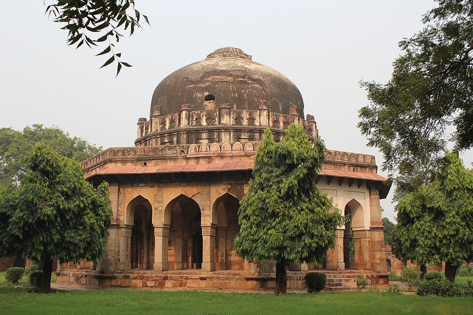 The octagonal tomb of Sikandar Lodi in Lodi Gardens, a single grey dome over an arcaded stone verandah with a crenellated parapet, standing on a lawn among trees