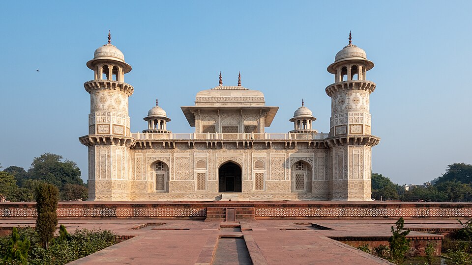 The white marble tomb of I'timad-ud-Daulah at Agra, a low square mausoleum inlaid with pietra dura, four octagonal corner minarets topped by domed kiosks, and a pavilion on the roof
