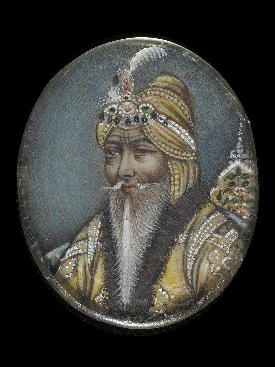 An oval miniature portrait of Maharaja Ranjit Singh in a jewelled turban with a white plume, white-bearded and wearing an embroidered robe