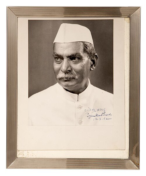 A framed, signed black-and-white portrait photograph of Rajendra Prasad wearing a white Gandhi cap and buttoned white coat
