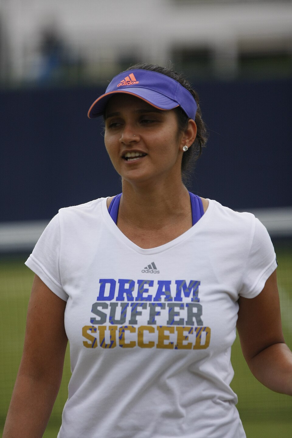 Indian tennis player Sania Mirza on a grass court, wearing a purple visor and a white training shirt