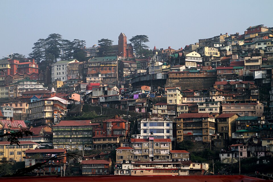 Shimla's houses stacked in tiers up a steep hillside, with the tower of Christ Church and a stand of deodars on the ridge above