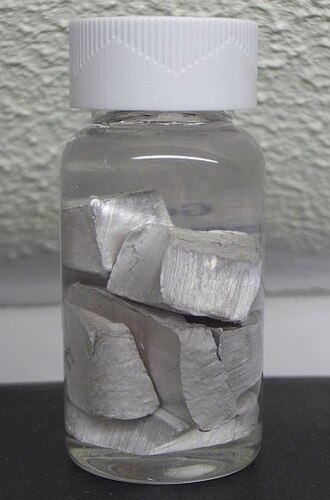 Chunks of silvery sodium metal stored under a layer of clear oil in a sealed glass bottle