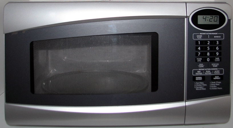 Front view of a silver countertop microwave oven with a mesh-screened glass door and a numeric keypad
