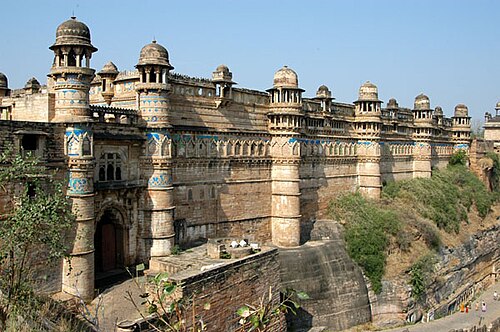 The eastern facade of Man Mandir Palace at Gwalior Fort, its round towers and cupolas banded with blue tilework above the cliff