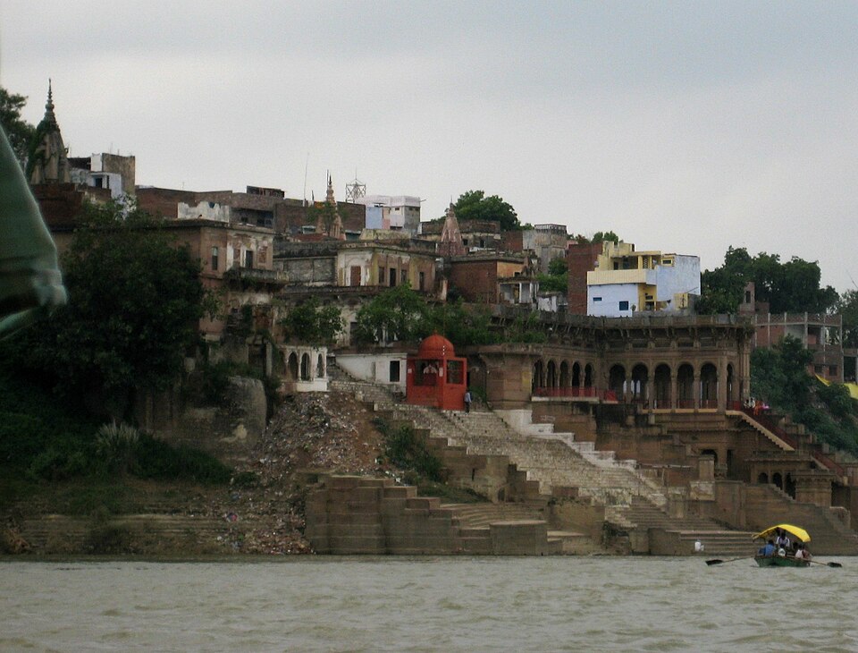 The stone ghats and riverfront buildings of Mirzapur rising above the Ganga, seen from the water