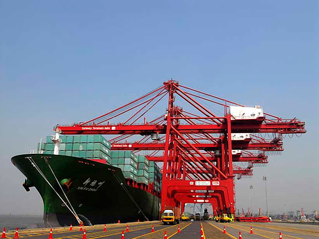 A container ship berthed at Jawaharlal Nehru Port beneath a row of red ship-to-shore gantry cranes marked Gateway Terminals India