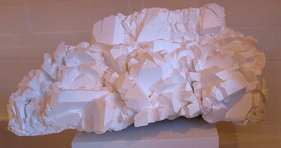 A large mass of white borax crystals with blocky faces, displayed on a plain plinth