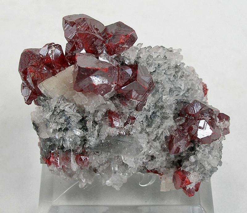 A cluster of deep red cinnabar crystals grown on white quartz and dolomite