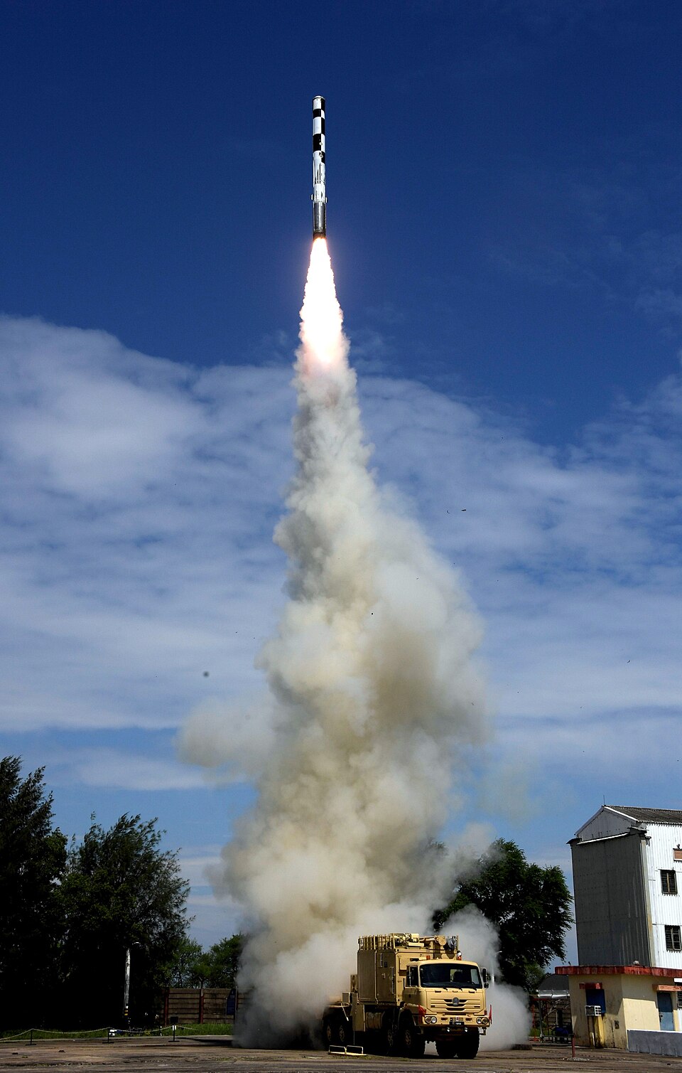 A BrahMos cruise missile climbing away from a road-mobile launcher vehicle during a test firing at a coastal test range