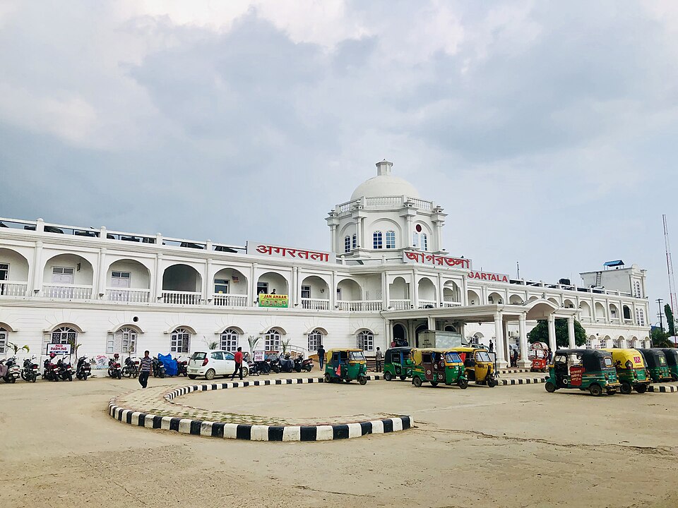 The white colonnaded frontage of Agartala railway station in Tripura, its name displayed in Hindi, Bengali and English above the arcade