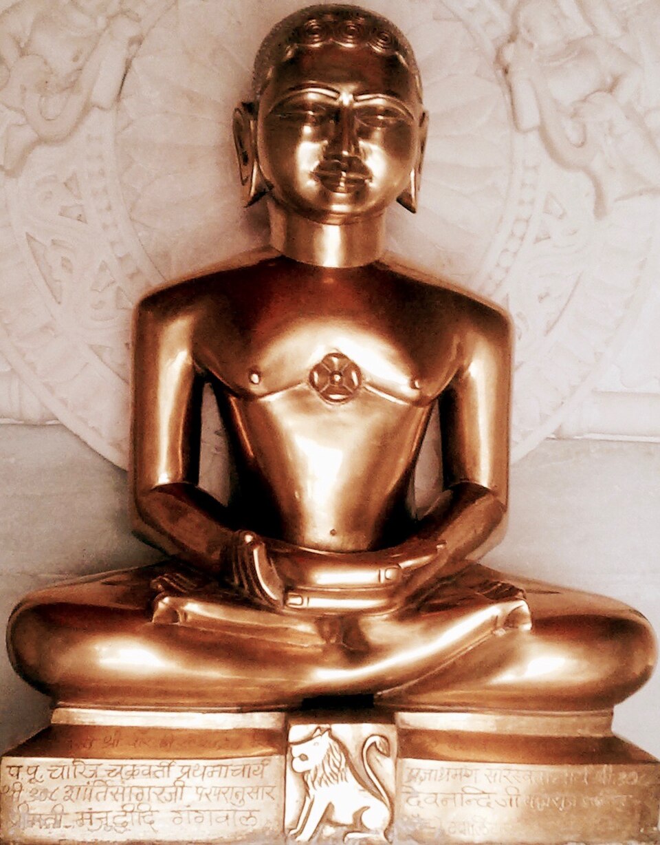 A polished golden idol of Mahavira seated cross-legged in meditation, the lion emblem of the twenty-fourth Tirthankara carved on the pedestal below him