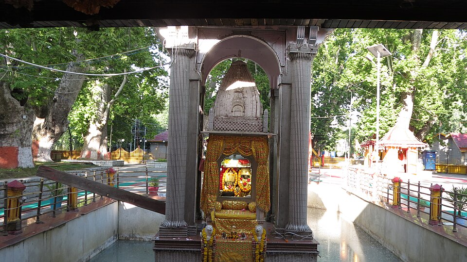 The small marble shrine of Kheer Bhawani, hung with marigold garlands, standing on a platform in the middle of its spring-fed tank with chinar trees around the courtyard