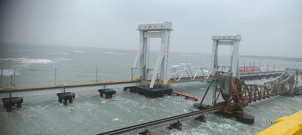 The new Pamban rail bridge across the sea, its two tall white towers carrying the vertical-lift span, with the rusted trusses of the old cantilever bridge alongside