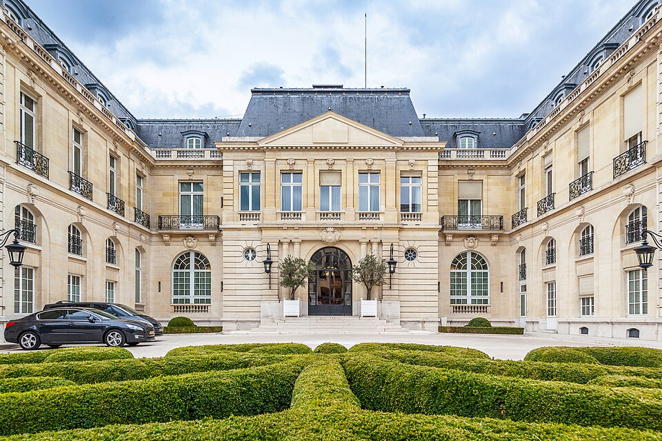 The curved stone facade and central pediment of the Chateau de la Muette in Paris, fronted by a clipped box parterre