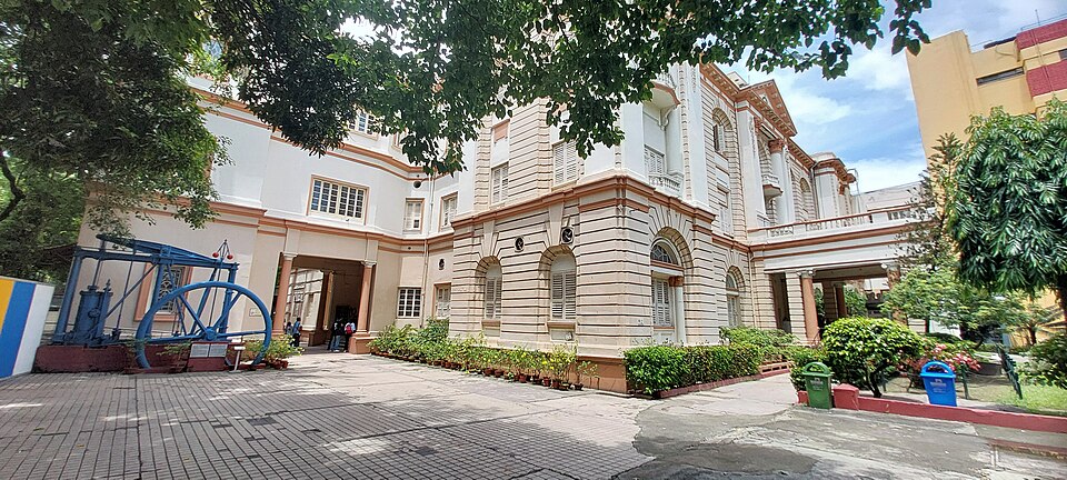 The colonial-era building of the Birla Industrial and Technological Museum in Kolkata, with a large blue beam engine displayed in the forecourt