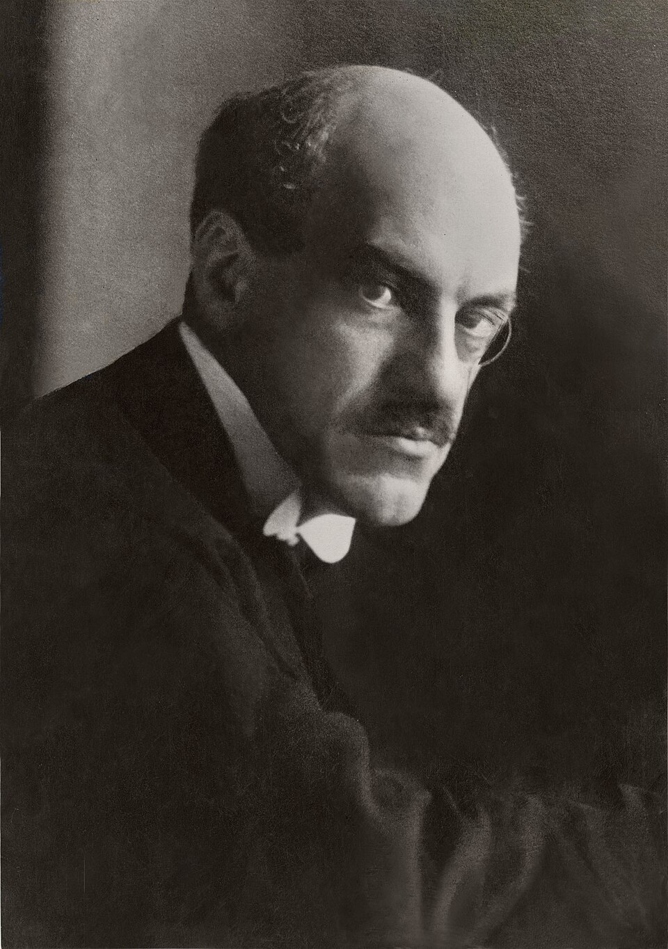 Black-and-white studio portrait of Edwin Samuel Montagu, a bald man with a moustache wearing a monocle and dark coat