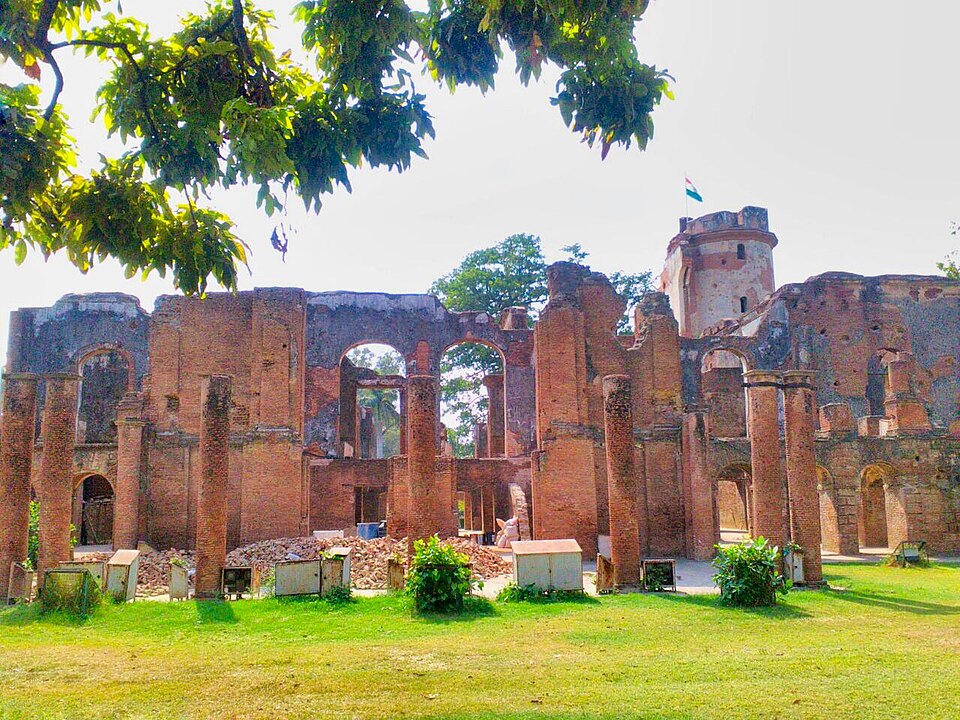 The roofless brick ruins of the British Residency at Lucknow, its shell-damaged walls and arches standing open to the sky with a flag flying from the surviving tower