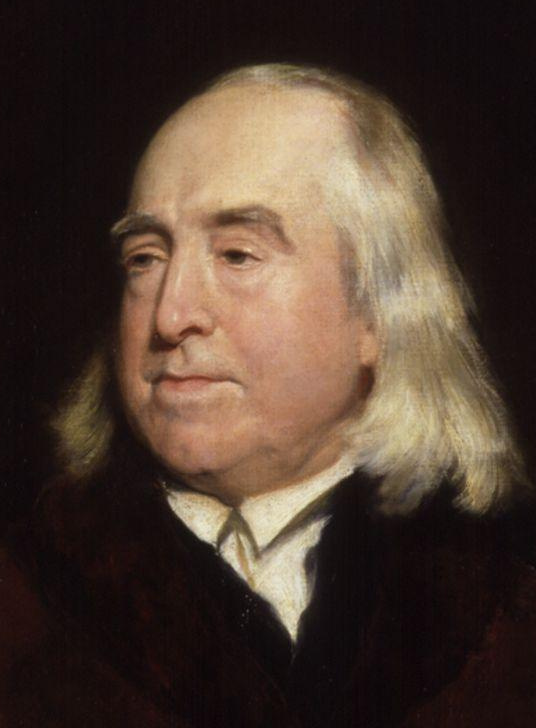 A painted head-and-shoulders portrait of Jeremy Bentham as an elderly man with long white hair, in a dark fur-collared coat.
