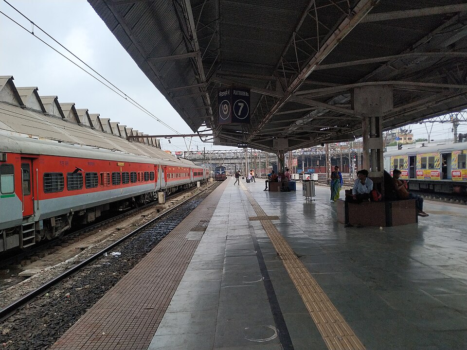 Platform 7 at Howrah Junction railway station in Kolkata, with a red passenger train standing at the platform under the station canopy and a hanging platform-number board.