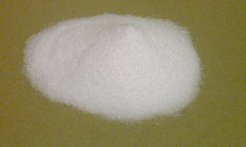 A small heap of fine white sodium bicarbonate (baking soda) powder on a plain surface.