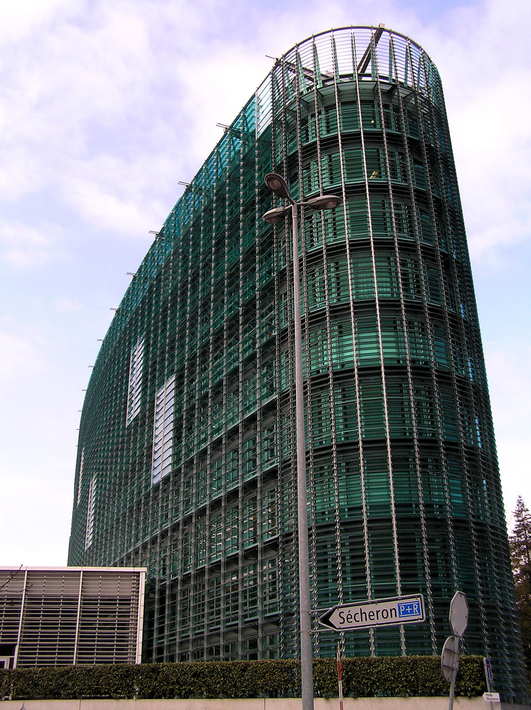 The World Meteorological Organization headquarters in Geneva, a curved building clad in green glass louvres, seen from the street below.