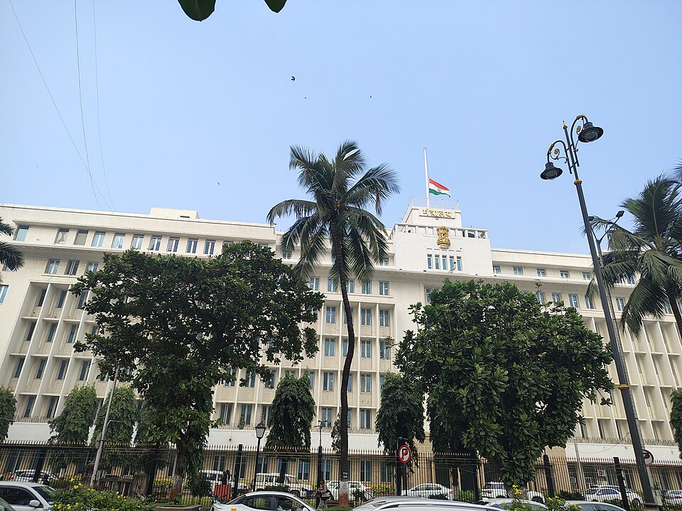 The white multi-storey Mantralaya building in Mumbai, the Maharashtra state secretariat, flying the Indian national flag with the State emblem on its facade.