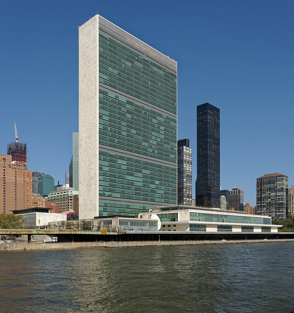 The green-glass United Nations Secretariat tower and the low General Assembly block at the United Nations Headquarters in New York, seen across the East River.
