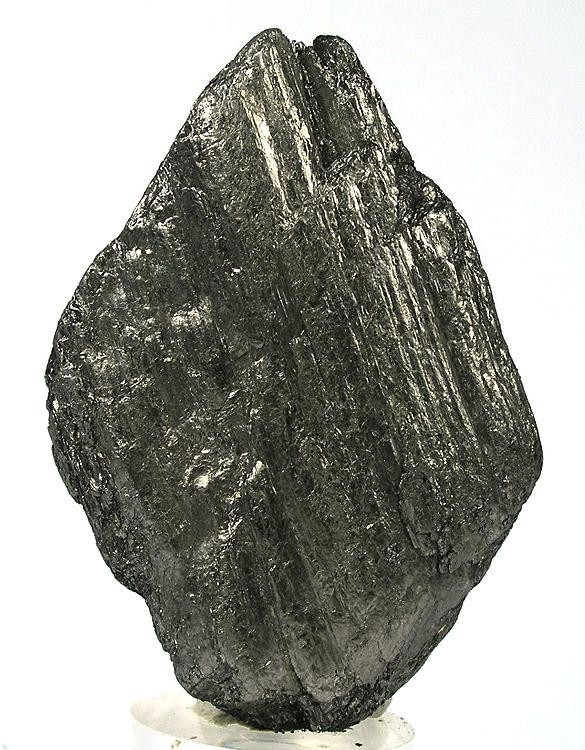 A dark grey specimen of graphite with a metallic sheen and layered, flaky faces, photographed against a white background.