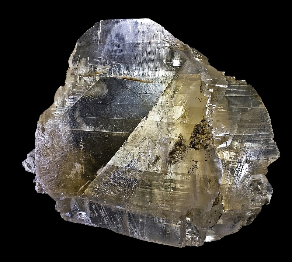 A translucent, pale honey-coloured gypsum crystal with flat twinned faces, photographed against a black background.