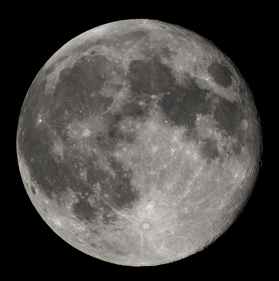 A sharp telescopic photograph of the nearly full Moon against black sky, showing its dark maria and bright cratered highlands.