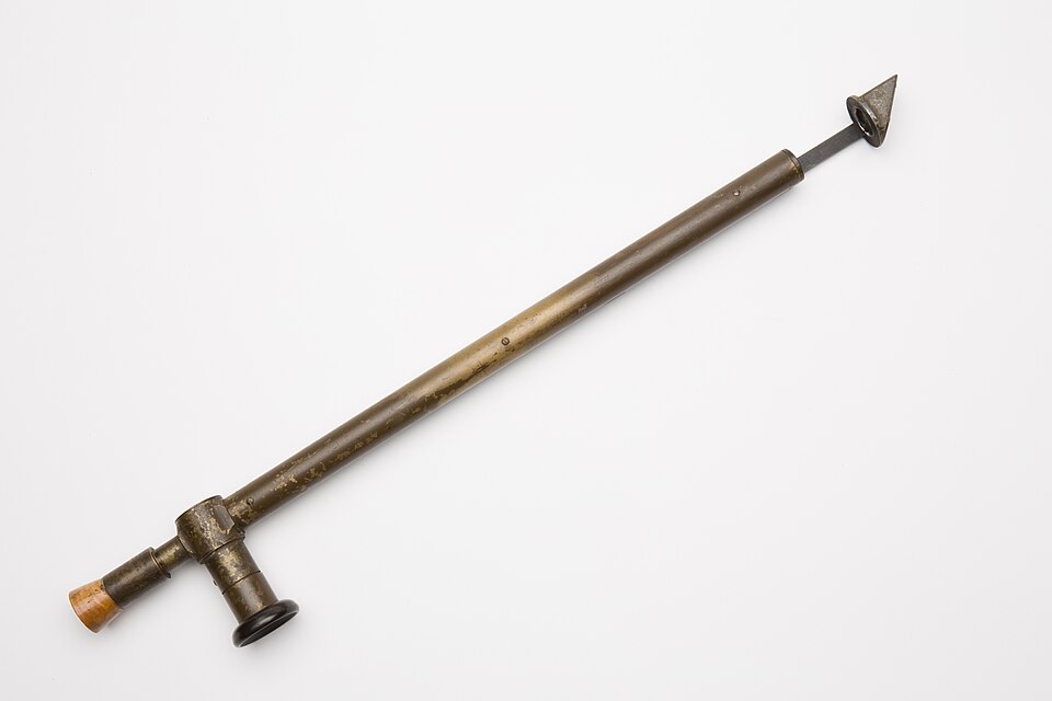 A brass trench periscope laid on a white background: a long tube with an angled viewing head at the top end and an eyepiece set at right angles near the bottom.