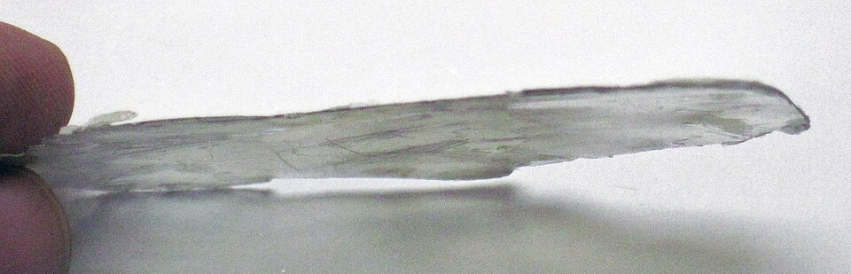 A thin, transparent, flexible cleavage sheet of muscovite mica held up to the light.
