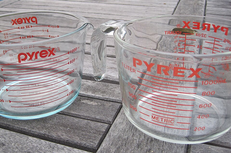 Two borosilicate Pyrex glass measuring jugs with red graduation markings.