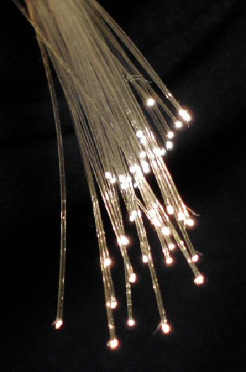 A bundle of glass optical fibres glowing with light emitted at their ends.