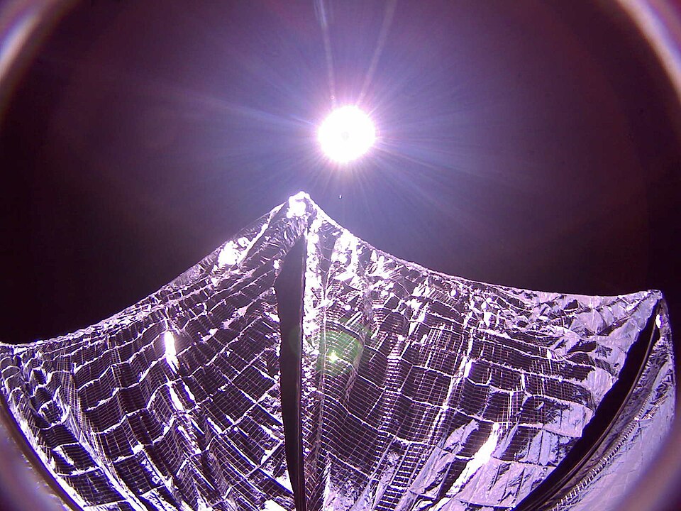 A solar sail spacecraft with its reflective sail fully deployed in space, propelled by sunlight