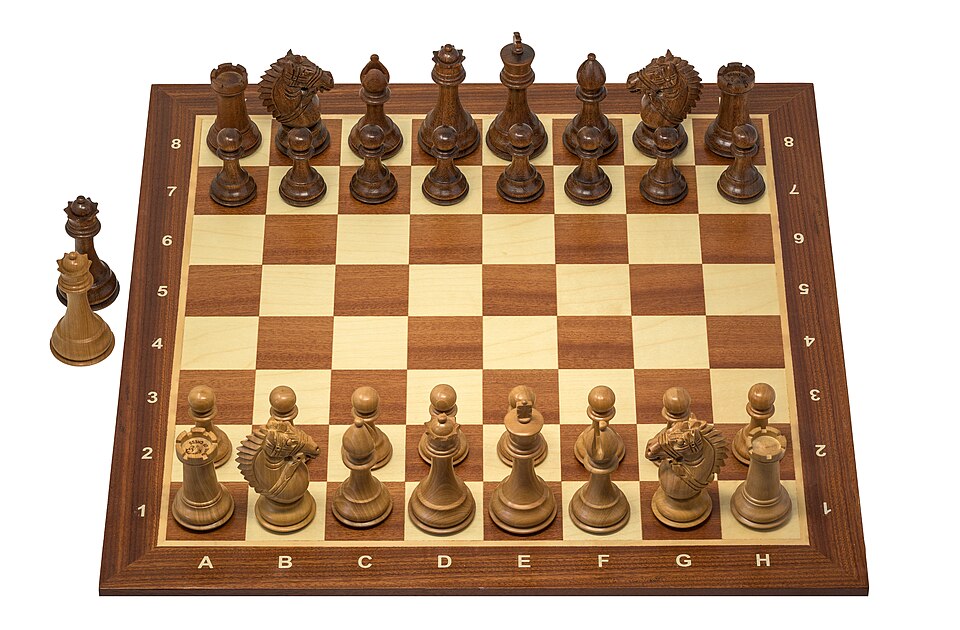A wooden chessboard with Staunton pieces set up for a game