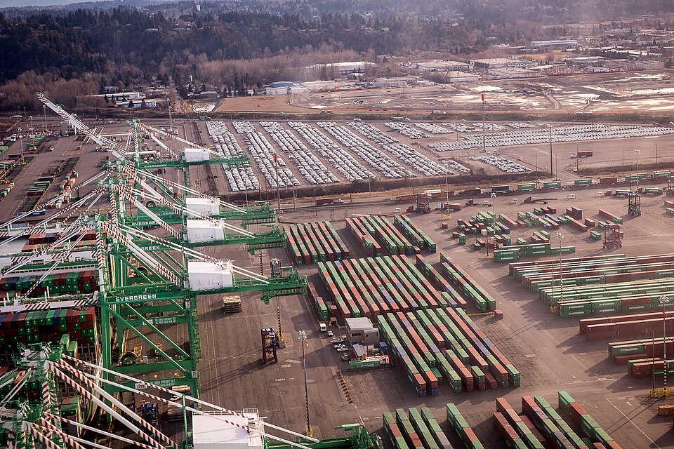 Gantry cranes and rows of stacked shipping containers at a large container sea port