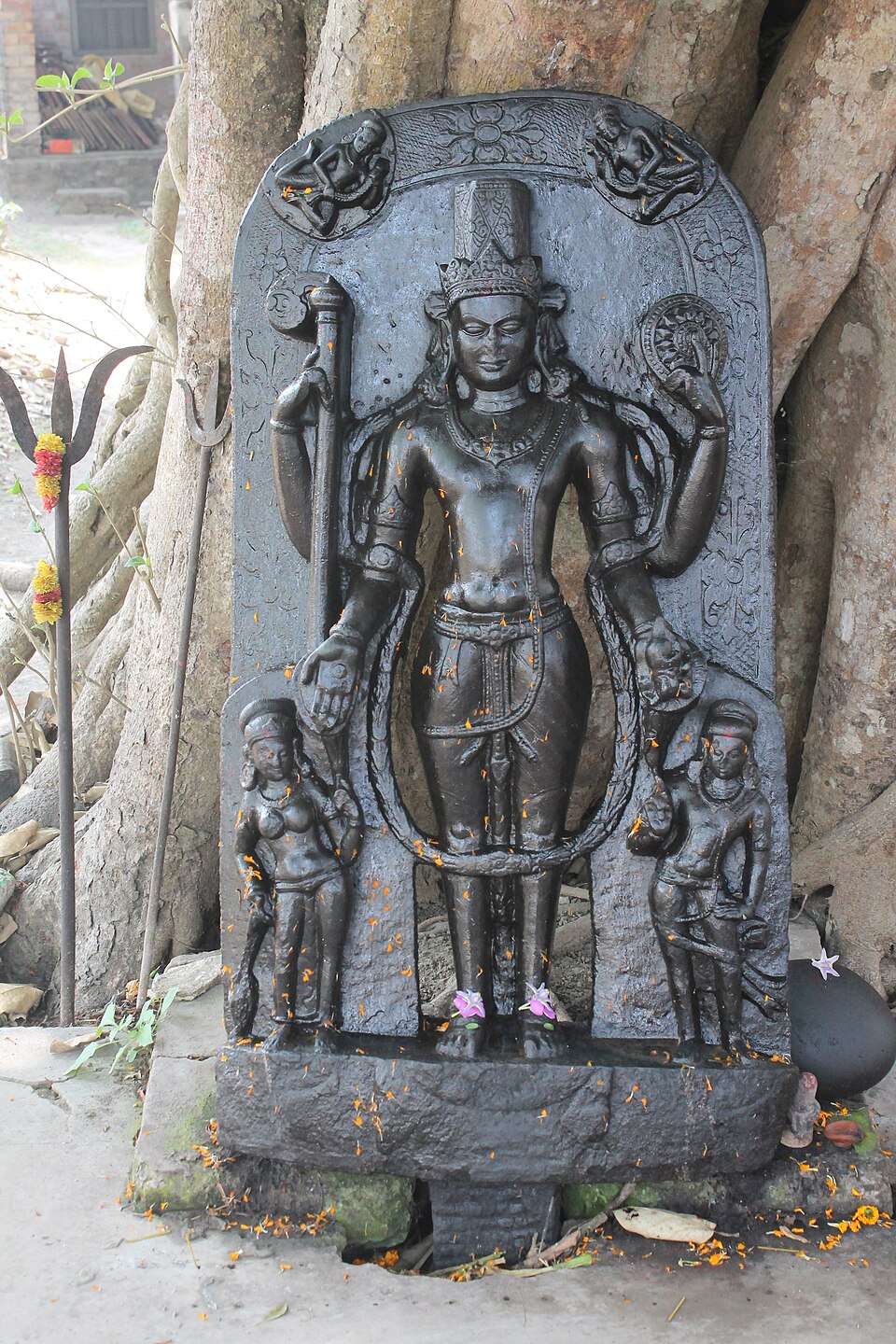 A black-stone anthropomorphic temple image of the god Vishnu with attendant figures