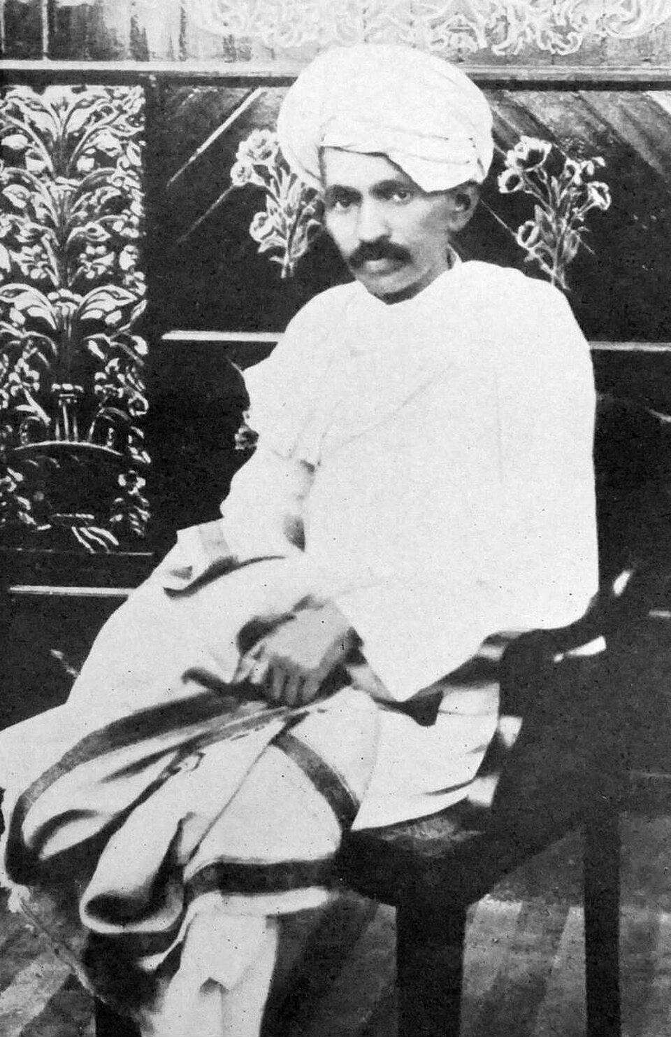 Mohandas K. Gandhi seated in 1918 at Kheda, in white dhoti and turban, a few years after his 1915 return to India